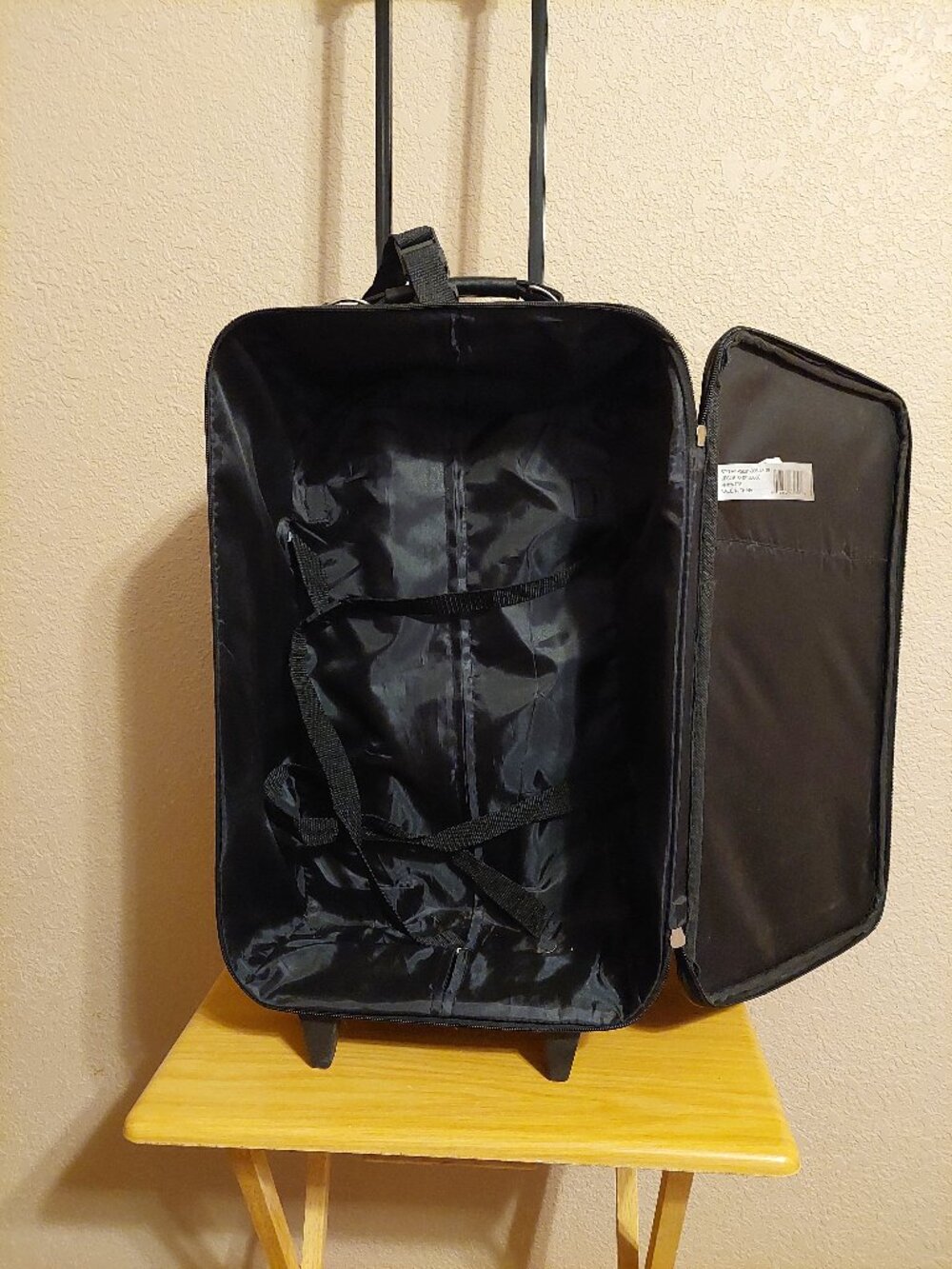 This is a black Protégé softside rolling carry-on suitcase featuring an exterior